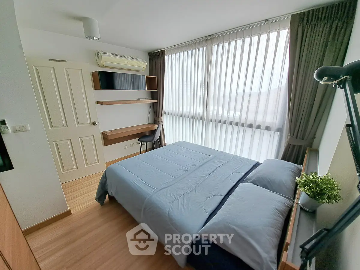 Modern bedroom with large window and stylish decor, perfect for relaxation and comfort.