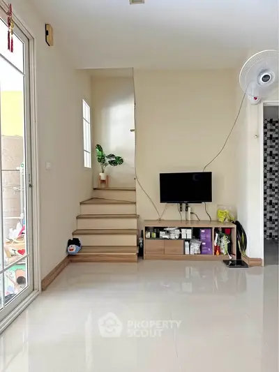 Modern living room with sleek staircase and wall-mounted TV, perfect for contemporary living.