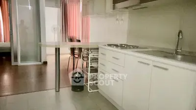 Modern kitchen with sleek white cabinets and open layout, adjacent to dining area with natural light.