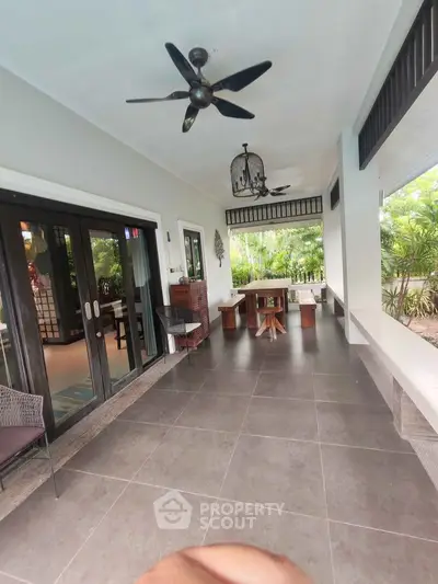 Spacious outdoor patio with modern furniture and ceiling fans, perfect for relaxation and entertaining.