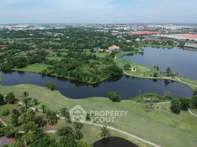 Stunning aerial view of lush green golf course with serene water features and expansive landscape.