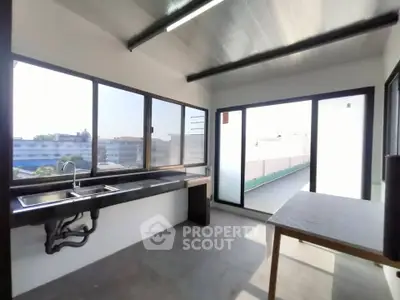 Spacious kitchen with large windows and modern design, offering ample natural light and a sleek countertop.