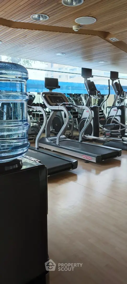 Modern gym with treadmills and water cooler in a well-lit fitness center.