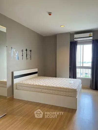 Spacious bedroom with modern decor and large window offering natural light.