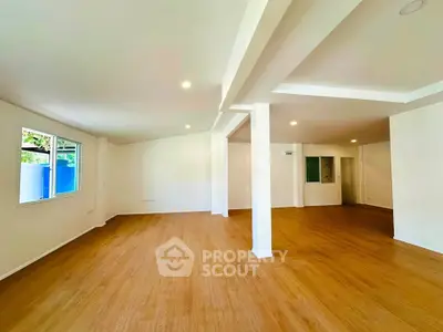 Spacious open-plan living room with wooden flooring and ample natural light.