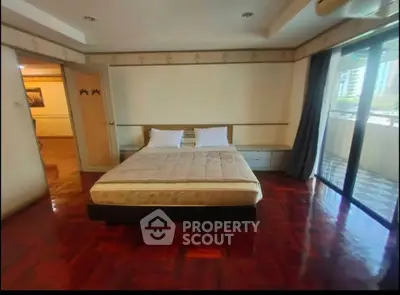 Spacious bedroom with large windows and polished wooden floors in a modern apartment.