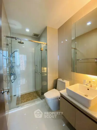 Modern bathroom with glass shower and sleek fixtures in a contemporary apartment.