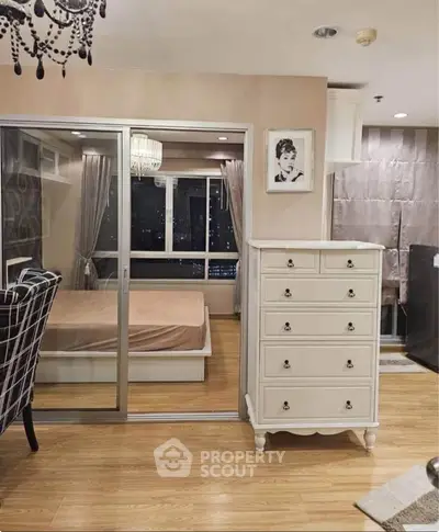 Stylish bedroom with elegant decor and city view, featuring a chic dresser and modern furnishings.