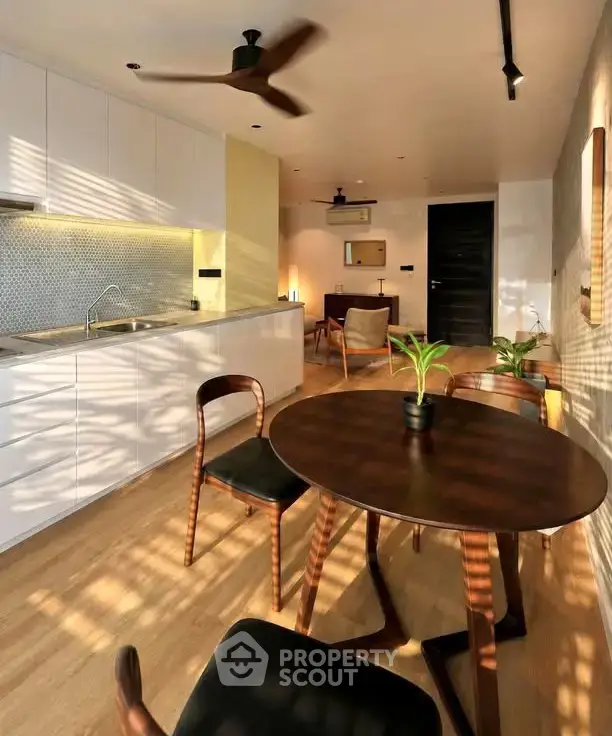 Modern open-layout kitchen and dining area with stylish furniture and warm lighting.