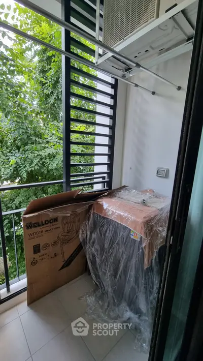 Compact balcony with air conditioning unit and lush greenery view