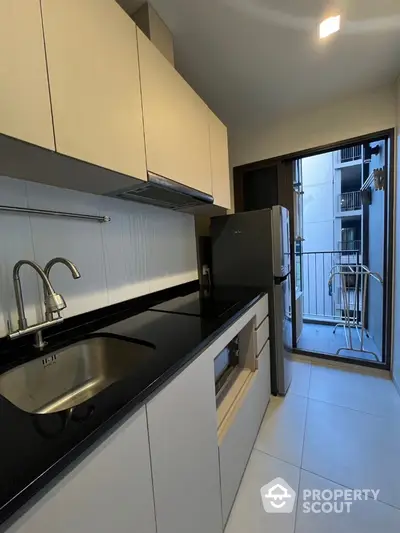 Modern kitchen with sleek cabinets and balcony access in urban apartment