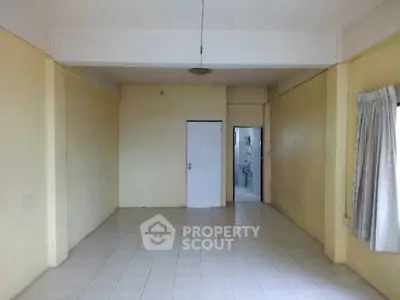 Spacious empty room with tiled floor and doorway leading to another area.