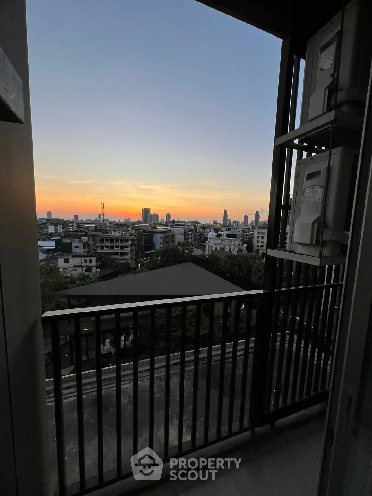 Stunning sunset view from a high-rise balcony overlooking the city skyline.