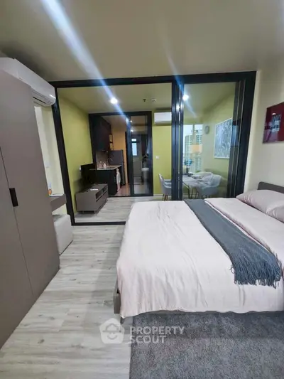 Modern studio apartment with open layout, featuring a cozy bedroom and compact kitchen area.