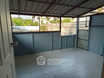 Spacious covered balcony with tiled floor and metal roof, ideal for outdoor relaxation.