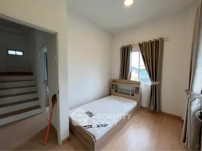 Cozy bedroom with wooden flooring and natural light, perfect for a serene living experience.