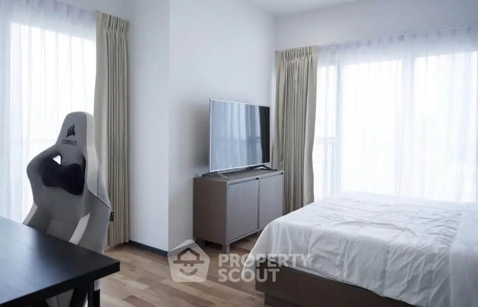 Modern bedroom with sleek furniture and large windows offering natural light.