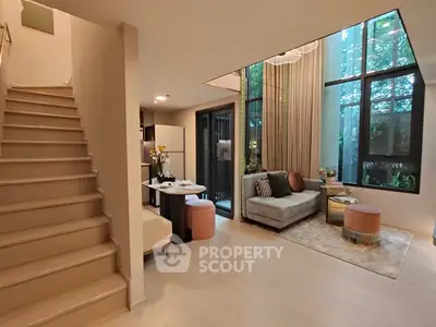 Modern living room with high ceilings and large windows offering a garden view.