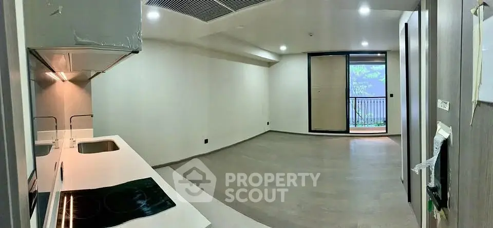 Modern open-plan living room with sleek kitchen and balcony access in a contemporary apartment.