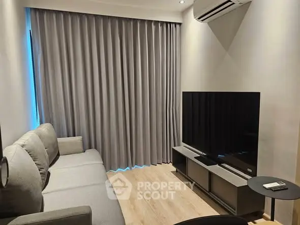 Modern living room with sleek furniture and large TV, featuring elegant curtains and wooden flooring.