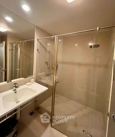 Modern bathroom with glass shower enclosure and sleek fixtures in a contemporary apartment.