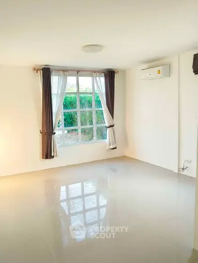 Spacious empty living room with large window and air conditioning unit.