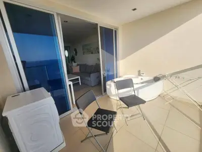 Spacious balcony with ocean view, featuring modern seating and a luxurious bathtub.