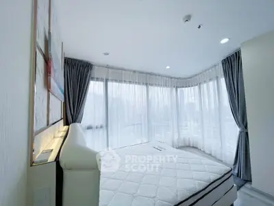 Spacious bedroom with large windows and city view, featuring modern decor and ample natural light.