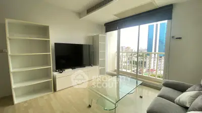 Modern living room with large TV, glass coffee table, and city view balcony.