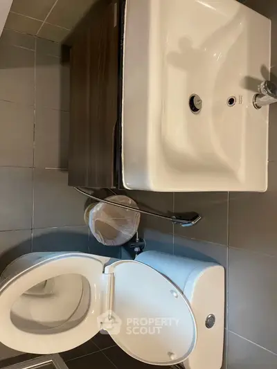 Modern bathroom with sleek sink and toilet design, featuring neutral tile flooring.