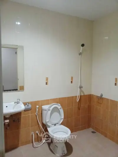 Spacious bathroom with modern fixtures and neutral tile design, featuring a shower and toilet.