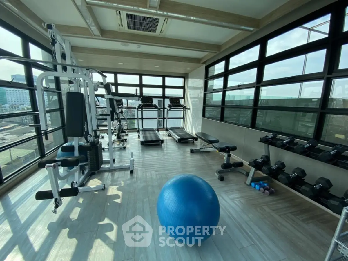 Modern gym with panoramic windows and fitness equipment in a high-rise building.