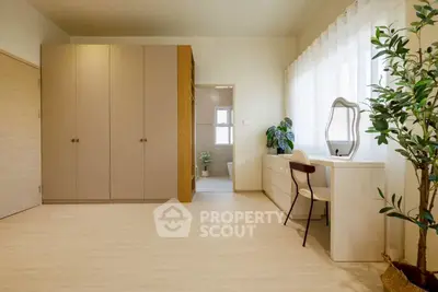 Spacious bedroom with elegant wardrobe and vanity, featuring natural light and minimalist decor.
