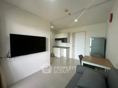 Modern apartment living room with sleek kitchen and dining area, featuring a wall-mounted TV and contemporary furniture.