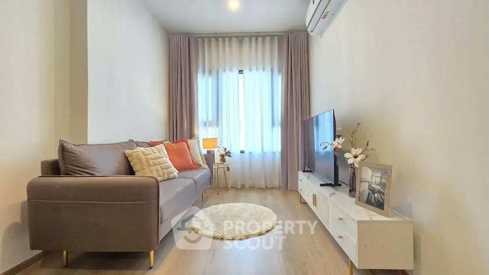 Modern living room with stylish decor, cozy sofa, and natural light through large window.