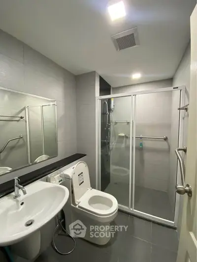 Modern bathroom with sleek design, featuring a glass shower enclosure and contemporary fixtures.