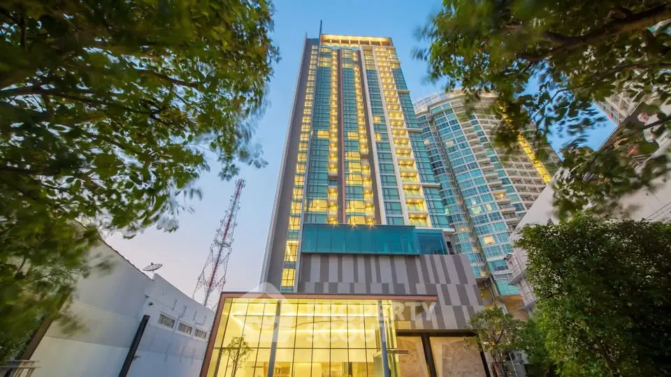 Stunning modern high-rise building with illuminated windows and lush greenery, perfect for urban living.
