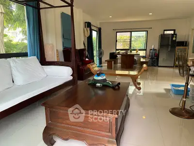 Spacious living room with elegant wooden furniture and large windows offering natural light.