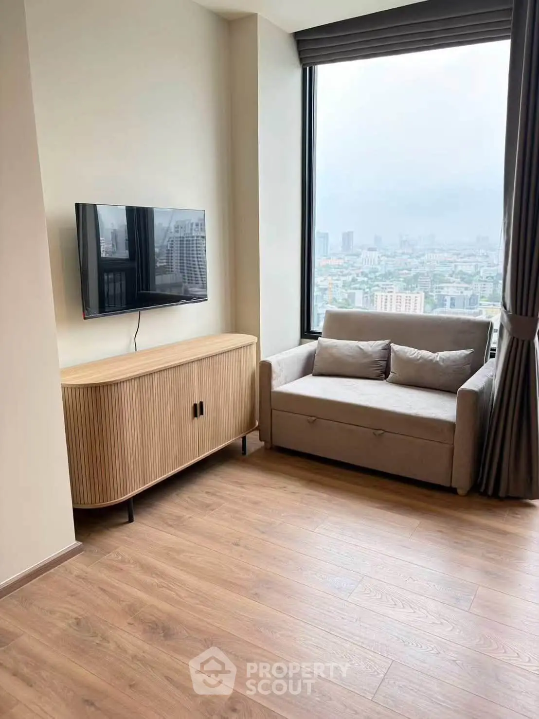 Modern living room with city view, featuring sleek TV setup and cozy seating area.