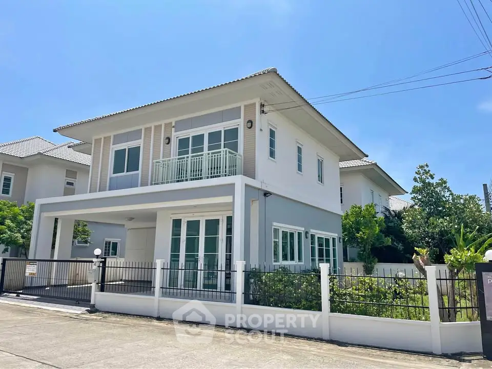 Modern two-story house with large windows and a fenced yard in a suburban neighborhood.