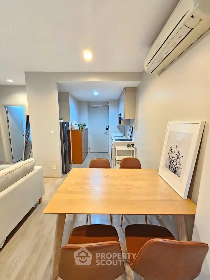 Modern dining area with wooden table and chairs, air conditioning, and stylish decor in a cozy apartment.