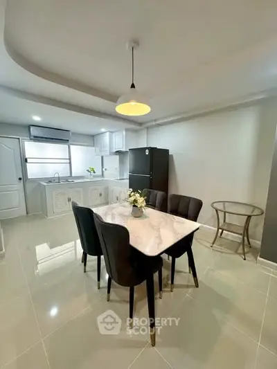 Modern kitchen with dining area featuring sleek marble table and elegant black chairs.