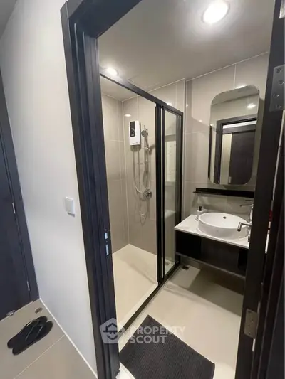Modern bathroom with sleek shower and stylish vanity in contemporary apartment.