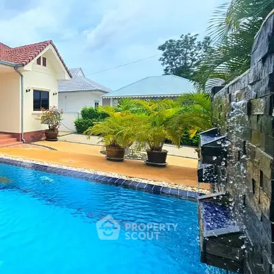 Stunning backyard pool with waterfall feature and lush landscaping in a serene residential setting.