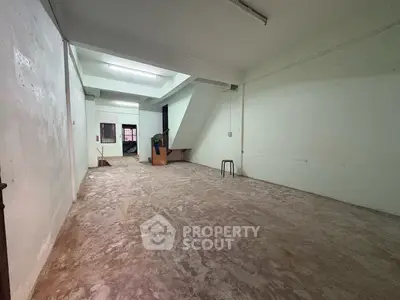 Spacious empty room with concrete floor and white walls, ideal for customization.