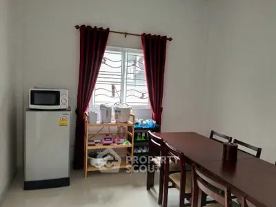 Cozy dining area with table, chairs, and kitchen appliances in a bright room.