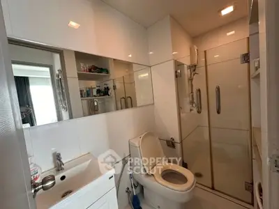 Modern bathroom with glass shower and sleek white fixtures in a contemporary apartment.