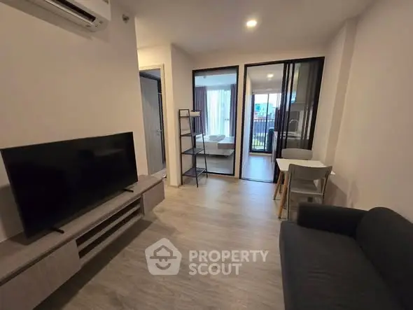 Modern living room with sleek furniture and open layout, featuring a TV and air conditioning.