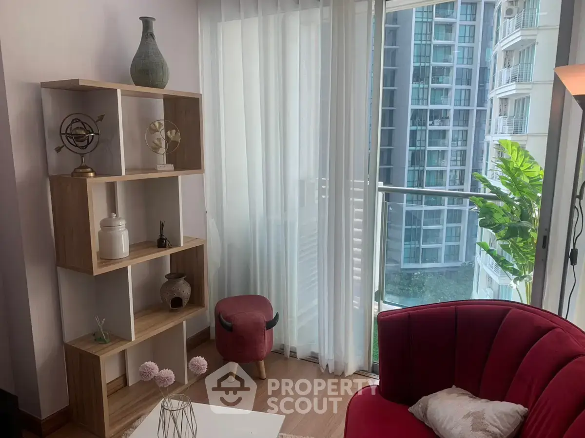 Chic modern living room with elegant decor and city view, featuring a stylish red chair and wooden shelving.