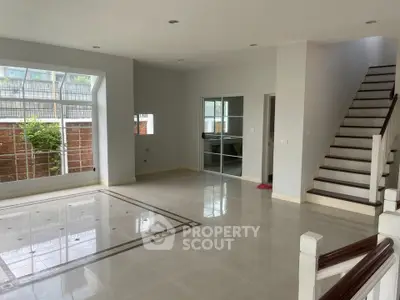 Spacious modern living room with large windows and elegant staircase